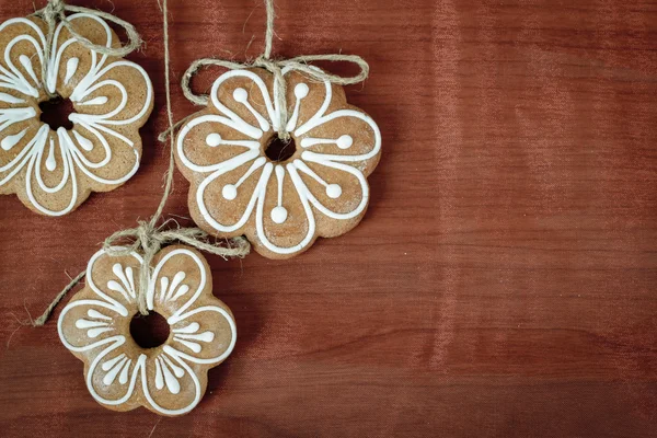 Gingerbread cookies hanging over wooden background — Stock Photo, Image