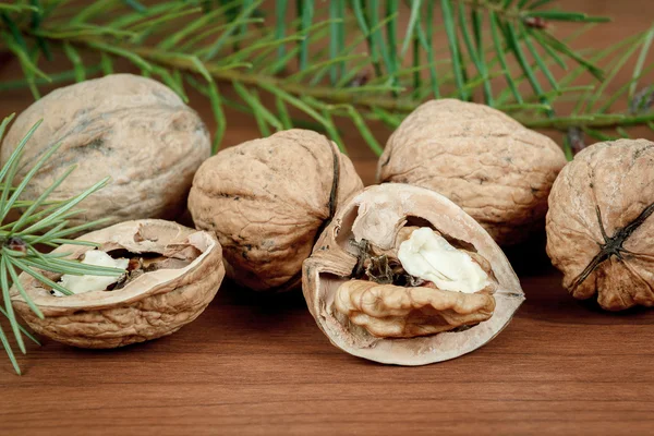 Walnuts and a cracked walnut on wooden background — Stock Photo, Image