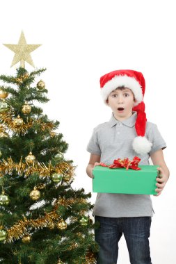 Happy boy in santa hat surprised by christmas present