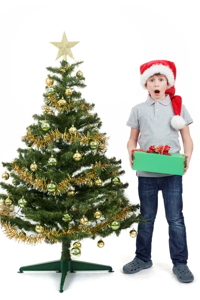 Happy boy in santa hat surprised by christmas present — Stok fotoğraf