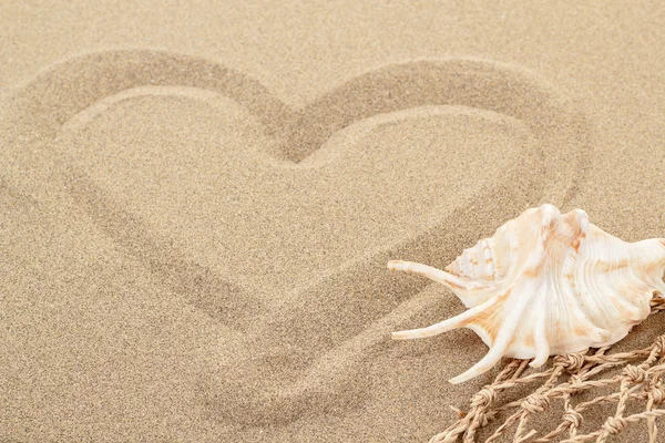 Handwritten heart on sand with seashell and shallow focus — Stock Photo, Image