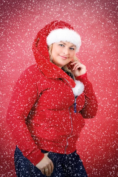 Mulher bonita alegre em chapéu vermelho de Papai Noel sorrindo com flocos de neve — Fotografia de Stock