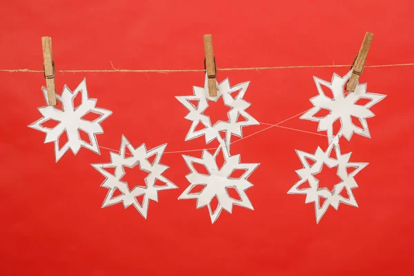 Flocos de neve produzidos por criança pendurada no fundo vermelho — Fotografia de Stock