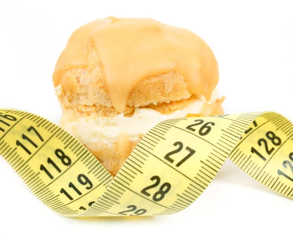 Concept of slimming, caramel cake with measuring tape — Stock Photo, Image