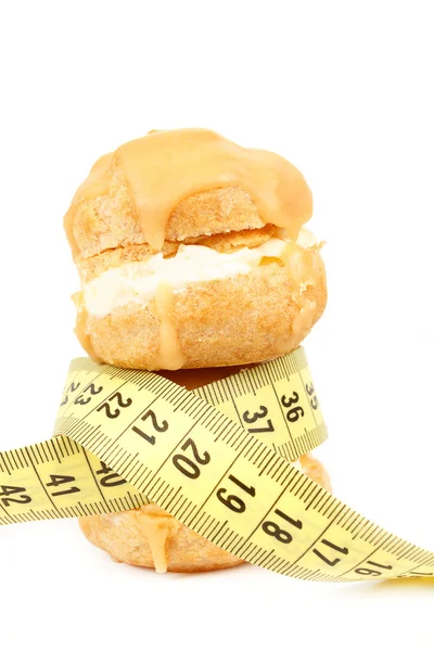 Concept of slimming, caramel cakes with measuring tape — Stock Photo, Image