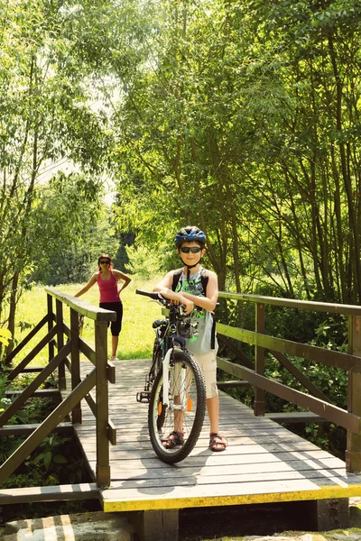 Adolescente relaxante em uma viagem de bicicleta na ponte de madeira — Fotografia de Stock