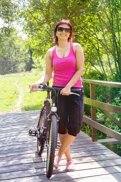 Bella donna con bicicletta su piccolo ponte di legno — Foto Stock