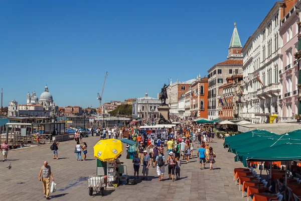 ITALY, VENICE - JULY 2012: Venice waterfront with crowd of tourist near St Marco Square on July 16, 2012 in Venice. St Marco Square is the largest and most f — Stock Photo, Image