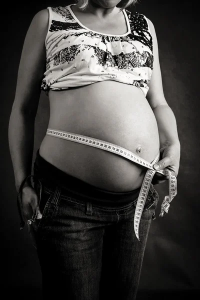 Pregnant woman tenderly measuring her tummy — Stock Photo, Image