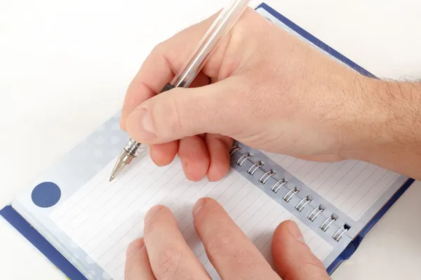 Close-up of hand beginning to write on notes — Stock Photo, Image