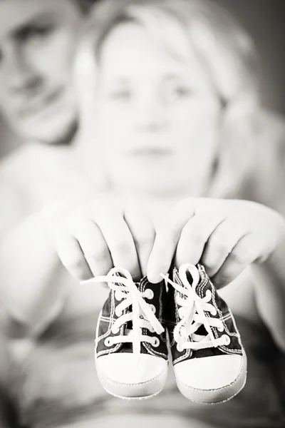 Pregnant woman and husband with a child's shoe — Stock Photo, Image