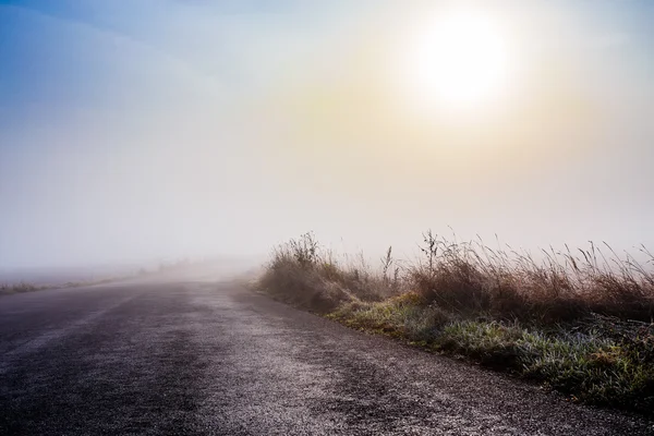 Estrada nebulosa rural que vai para o nascer do sol — Fotografia de Stock