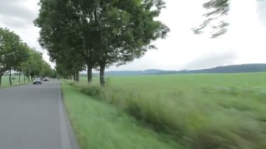 Bir ülkede yol boyunca bir araba, bisikletçi ve araçların karşılamak yazında, geniş vurdu