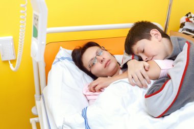 üzgün orta yaşlı bir kadın ile oğlu hastaneye yatan
