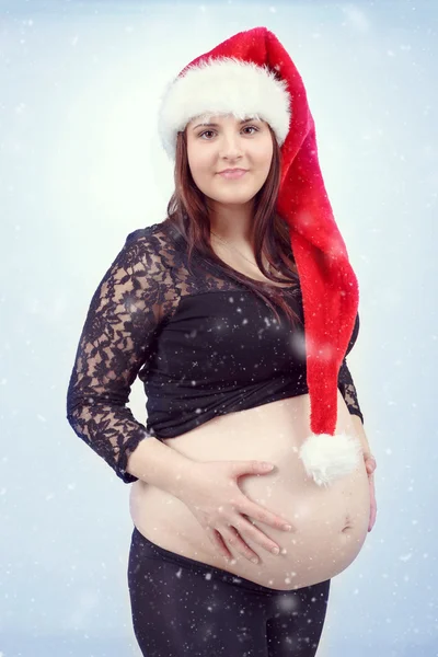 Beautiful pregnant santa woman tenderly holding her tummy — Stock Photo, Image