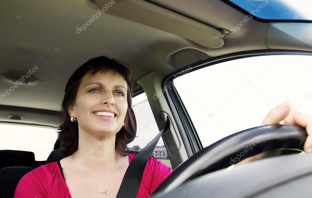 Smiling brunette woman driving car