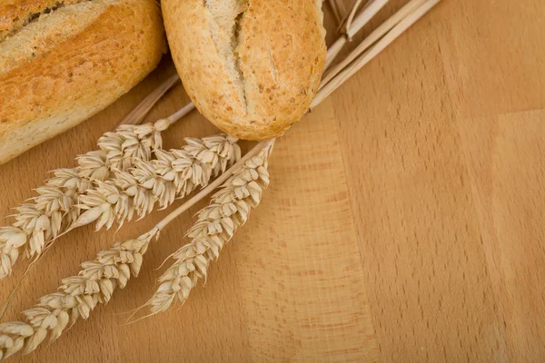 Rollo sobre mesa de madera con espigas de grano de trigo —  Fotos de Stock