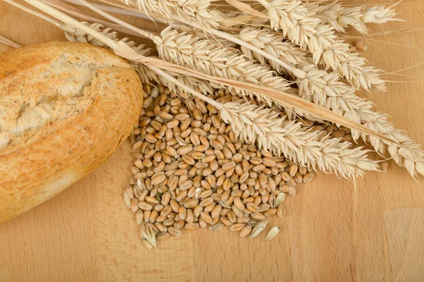 Rollo sobre mesa de madera con espigas de grano de trigo —  Fotos de Stock