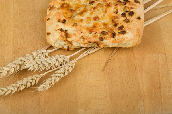 Frisches Brot mit Käse und Zwiebeln auf Holztisch mit Ähren — Stockfoto