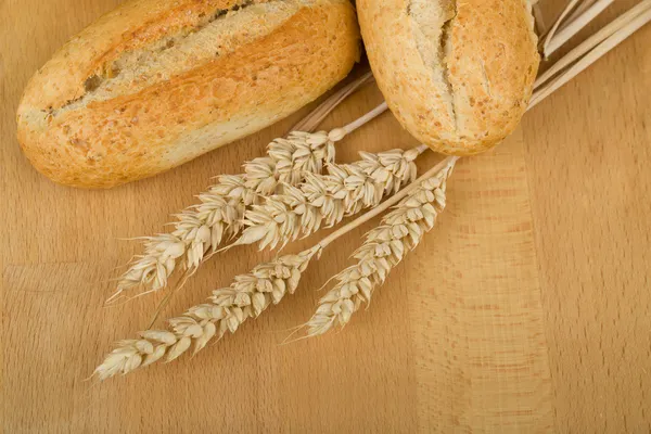 Rollo sobre mesa de madera con espigas de grano de trigo —  Fotos de Stock