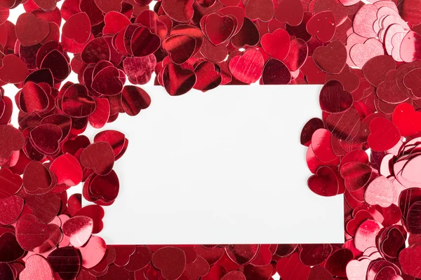 Small red confetti and big hearts on white background — Stock Photo, Image