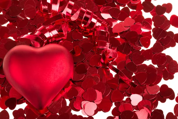 Pequeno confete vermelho e corações grandes no fundo branco — Fotografia de Stock