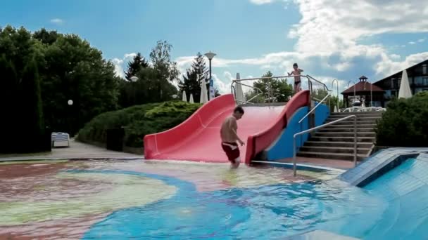 Niños felices en tobogán en la piscina al aire libre de verano — Vídeo de stock