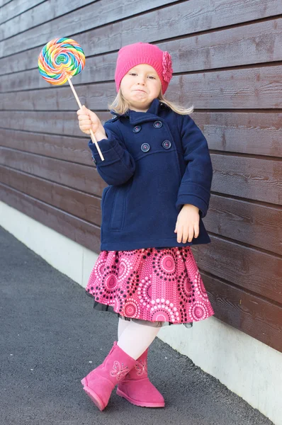 Flicka i rosa klänning visar lollypop — Stockfoto