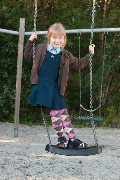 Meisje in school uniform op een schommel — Stockfoto