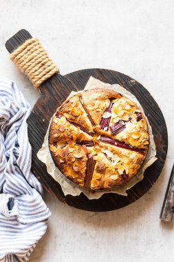 Rhubarb keki ahşap servis tahtasının üzerinde servis ediliyor. Pastanın altında da bir parça kağıt var.