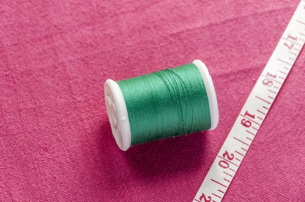 Carrete de algodón y cinta métrica sobre fondo textil de algodón — Foto de Stock