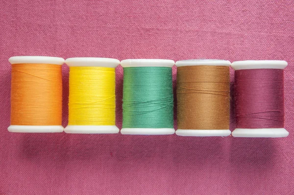 Colourful cotton reel on cotton textile background — Stock Photo, Image