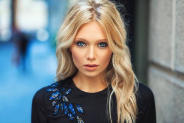 Çekici genç sarışın kız Milano 'da uzun siyah gece elbisesi içinde yürüyor ve poz veriyor.