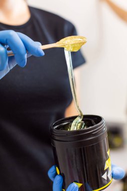 Profesyonel şeker tutucu, siyah kavanoz. Yakından bir çubukla balmumu karıştırıyor.