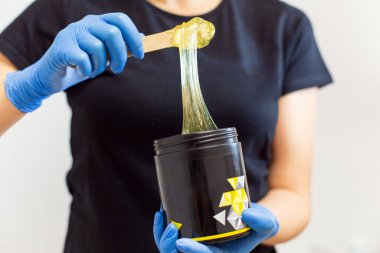 Profesyonel şeker tutucu, siyah kavanoz. Yakından bir çubukla balmumu karıştırıyor.