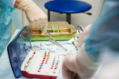 Ameliyat sırasında hastanede dişçi aletleriyle birlikte masanın yanında stomatolojik aletler tutan profesyonel bir dişçi.