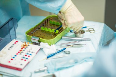 Ameliyat sırasında hastanede dişçi aletleriyle birlikte masanın yanında stomatolojik aletler tutan profesyonel bir dişçi.