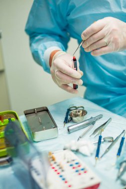 Ameliyat sırasında hastanede dişçi aletleriyle birlikte masanın yanında stomatolojik aletler tutan profesyonel bir dişçi.