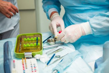 Ameliyat sırasında hastanede dişçi aletleriyle birlikte masanın yanında stomatolojik aletler tutan profesyonel bir dişçi.