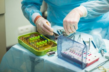 Ameliyat sırasında hastanede dişçi aletleriyle birlikte masanın yanında stomatolojik aletler tutan profesyonel bir dişçi.