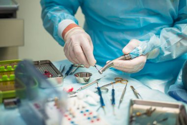 Ameliyat sırasında hastanede dişçi aletleriyle birlikte masanın yanında stomatolojik aletler tutan profesyonel bir dişçi.