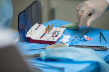 Ameliyat sırasında hastanede dişçi aletleriyle birlikte masanın yanında stomatolojik aletler tutan profesyonel bir dişçi.