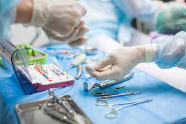 Ameliyat sırasında hastanede dişçi aletleriyle birlikte masanın yanında stomatolojik aletler tutan profesyonel bir dişçi.