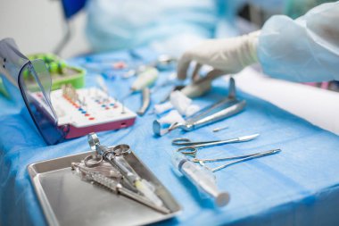 Ameliyat sırasında hastanede dişçi aletleriyle birlikte masanın yanında stomatolojik aletler tutan profesyonel bir dişçi.