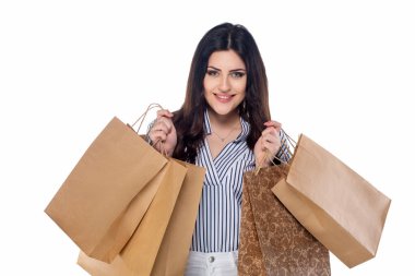 Beyaz pantolonlu, çizgili tişörtlü beyaz arka planda izole edilmiş alışveriş torbaları taşıyan güzel esmer beyaz kız.