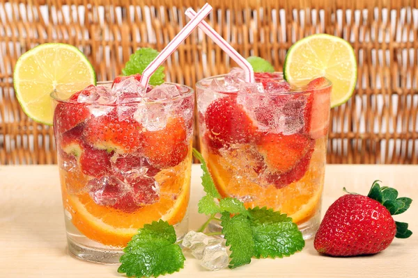 Boisson colorée avec orange, fraise, citron vert et glace — Photo