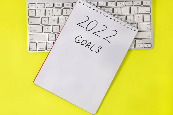 2022 goals with keyboard on yellow background. New Year resolutions and goal setting concept.