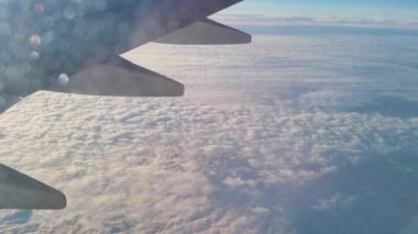 Uçak penceresinin manzarası. Mavi gökyüzü bulutlarının üzerinde uçan bir uçağın kanadı. Uçuş, seyahat. Süper yavaş çekim.