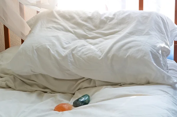 Pillow on bed with healing stones — Stock Photo, Image