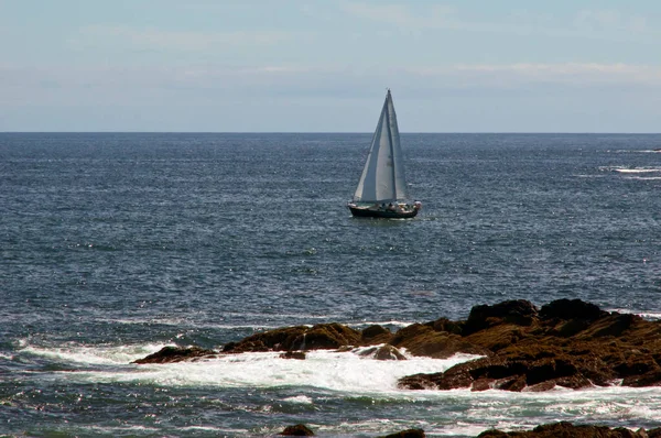 午後の晴れた日には 大西洋の岩場の海岸線の近くに帆船が浮かんでいます — ストック写真